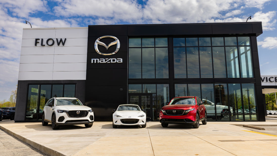 A lineup of Mazda cars parked outside of the Flow Mazda of Greensboro dealership