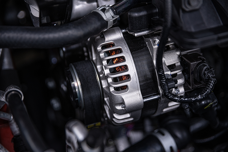 Close-up of a car engine alternator with its pulley and visible copper windings.